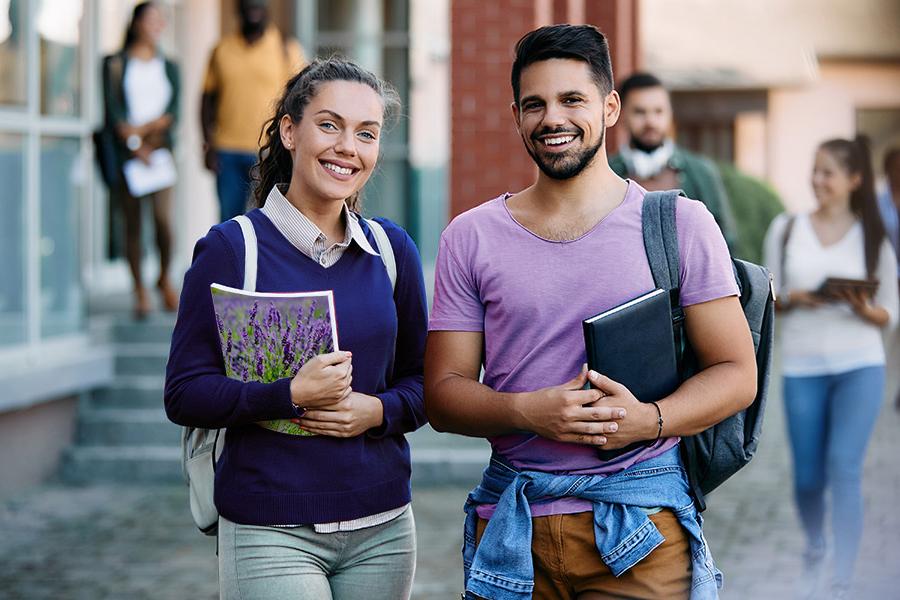 2个微笑的大学生. 一名学生穿着淡紫色的t恤，另一名学生拿着一本笔记本，背面画着一片薰衣草田.